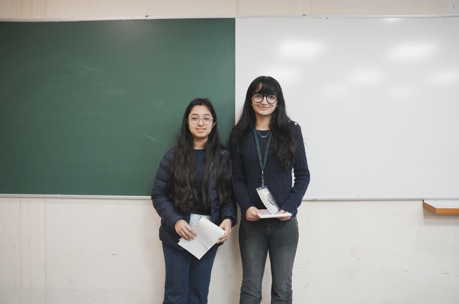Two students standing at the board with their notes, ready to speak