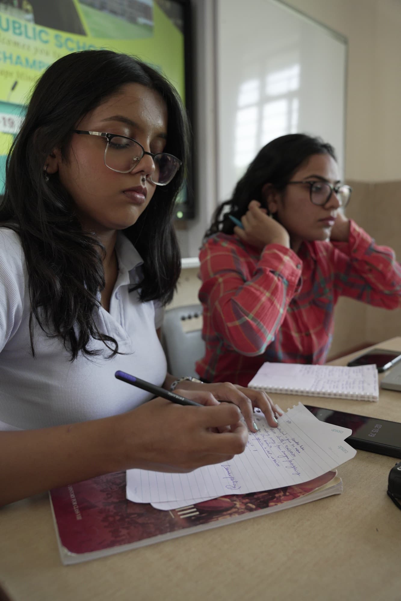 Two students drafting debate cases at their desks during an in-school championship
