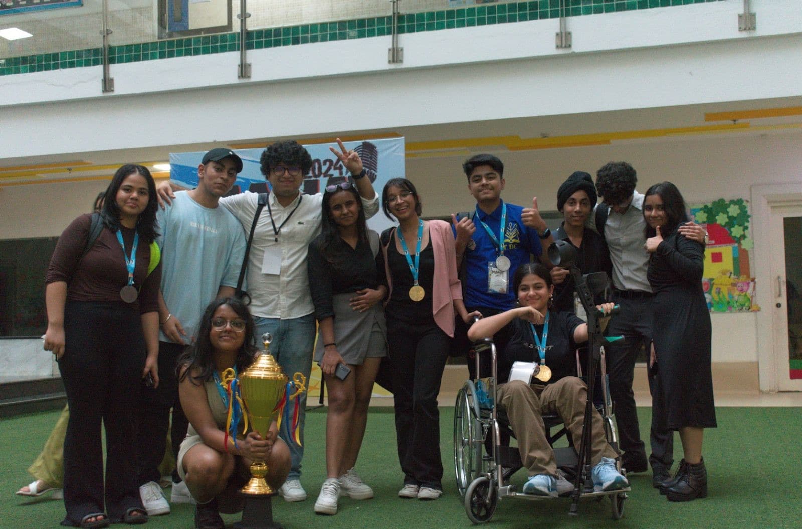 A cohort of eleven students posing with a trophy