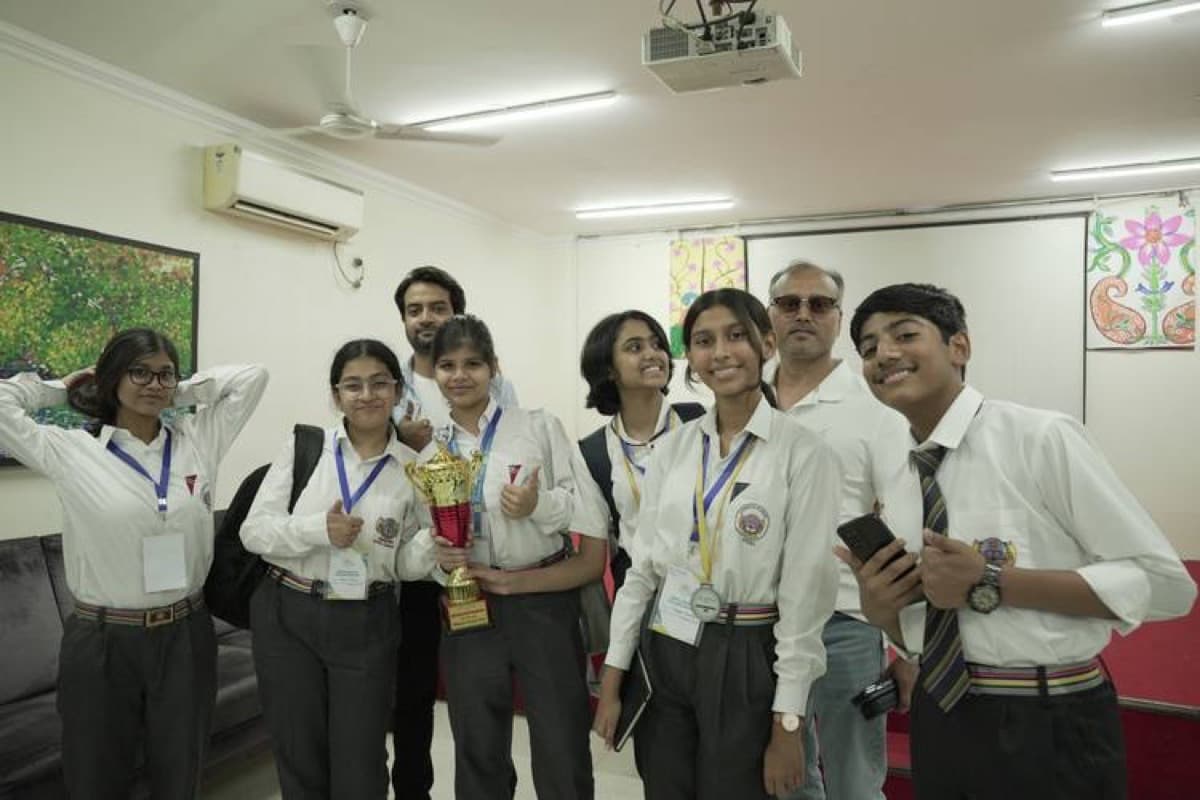 Eight uniformed students and two coaches holding a gold trophy