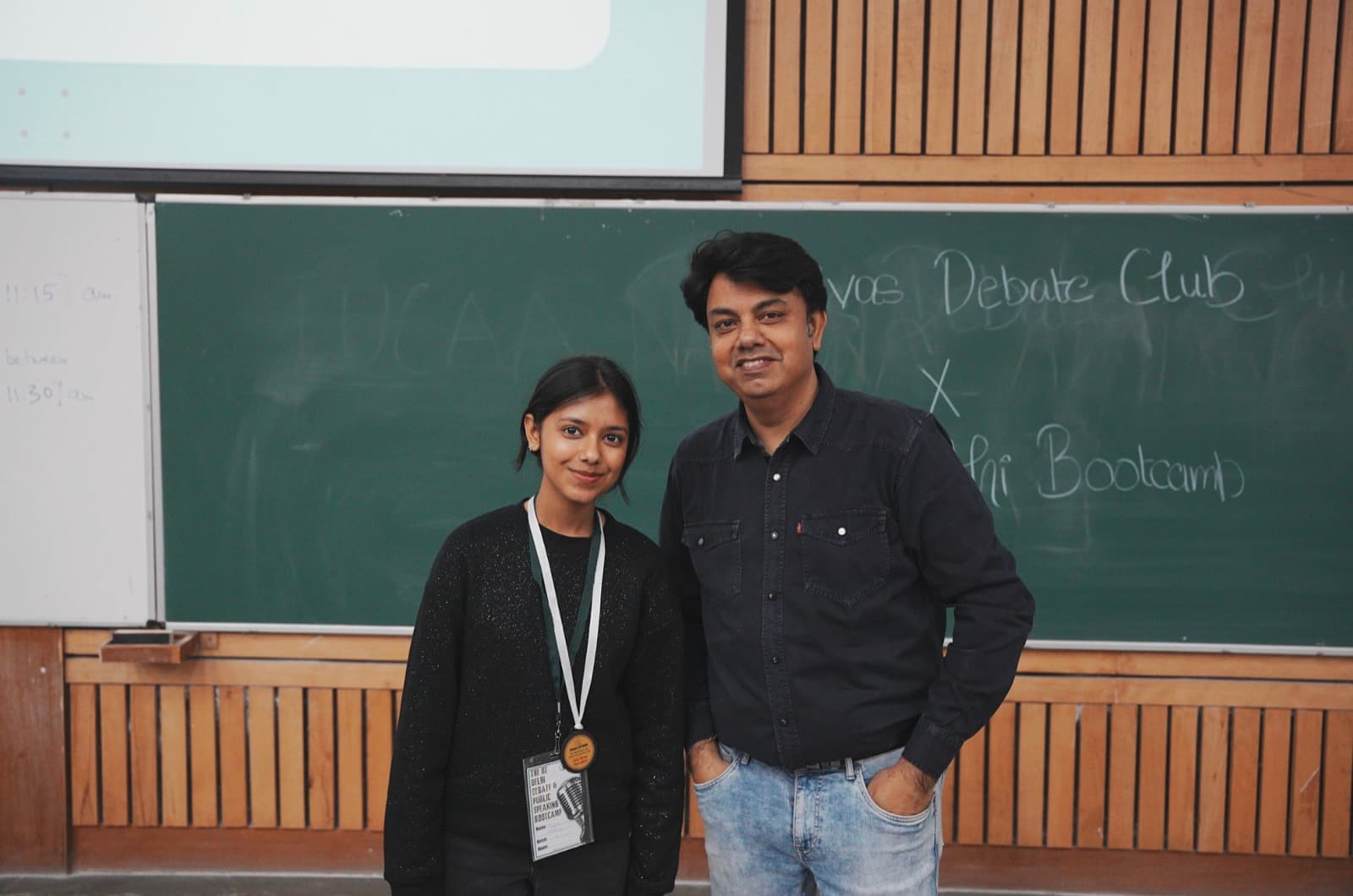 A student holding a medal beside a coach in front of a blackboard reading IIT Delhi Bootcamp
