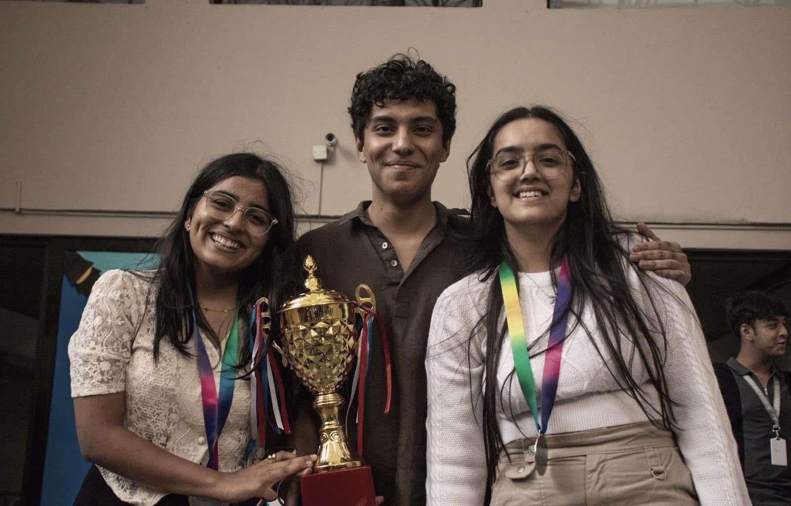 Three students holding a trophy after a debate final