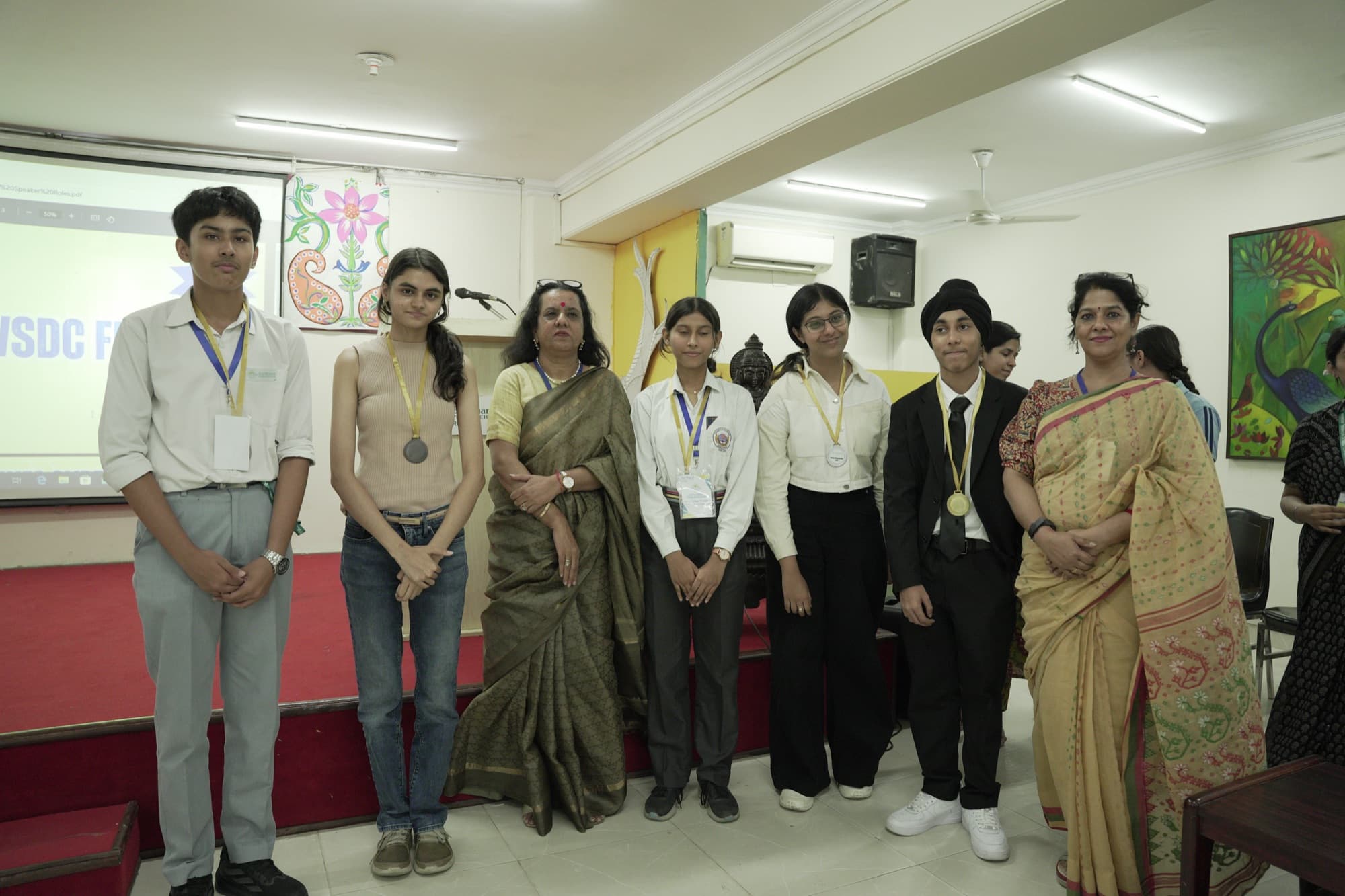 Six students with medals standing with their teachers